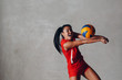 © primipil - Young smiling Asian woman volleyball player in red uniform with ball