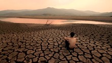 Asian Children Sitting Near The Last Water Source That Drying Everyday With Sadness And Hopeless On Summer. Water Crisis And Climate Change Impact Rivers Drying With Skinny Man Sitting On Dry Cracked 