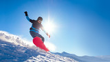 Snowboarder Riding Red Snowboard on the Slope in the Mountains in Bright Sun. Snowboarding and Winter Sports Concept