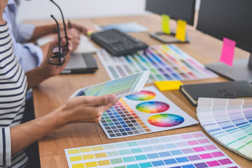 Poster - Two colleagues creative graphic designer working on color selection and drawing on graphics tablet at workplace, Color swatch samples chart for selection coloring