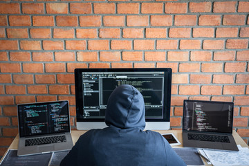 Wall Mural - Computer hacker or cyber attack concept, Dangerous hooded hacker using multiple computers typing bad data into online system the access with a virus to infect steal information