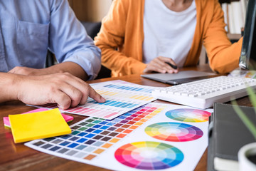 Poster - Two colleagues creative graphic designer working on color selection and drawing on graphics tablet at workplace