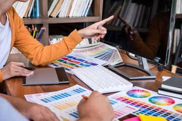 Poster - Two colleague creative graphic designer working on color selection and color swatches, drawing on graphics tablet at workplace with work tools and accessories