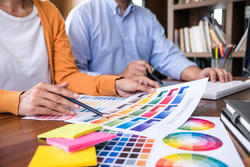 Poster - Two colleague creative graphic designer working on color selection and color swatches, drawing on graphics tablet at workplace with work tools and accessories