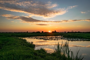 Wall Mural - sun goes down over the polder landscape in holland. beautiful colors and reflections in the water.