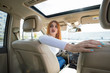 © bilanol - Wide angle view of young redhead woman driver driving a car backwards looking behind.