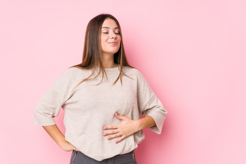 Wall Mural - Young caucasian woman posing isolated touches tummy, smiles gently, eating and satisfaction concept.