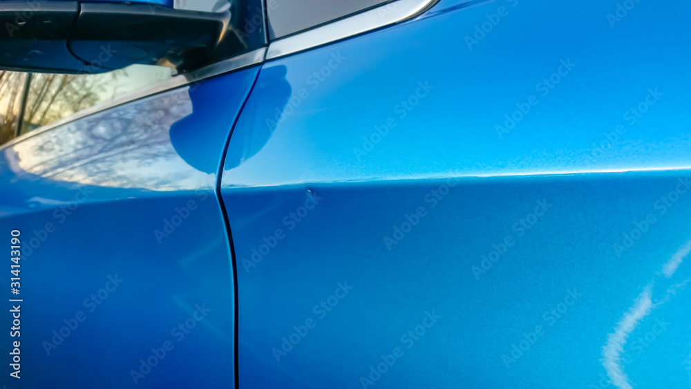 A small dent in the fender of a blue metallic European car - obrazy, fototapety, plakaty 