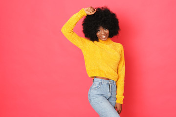 Wall Mural - Happy afro-amercian girl in hello sweater isolated on red background.