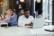 © gorynvd - Serious dark-skinned young office manager works with different reports and table laptop at his workplace in the meeting room at modern business centre.