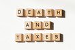 © Richard - Wooden letter block tiles spelling out 'DEATH AND TAXES' on white background.