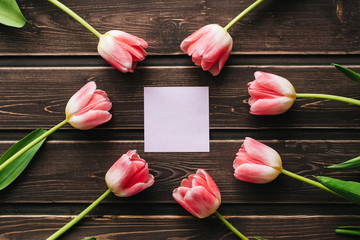 Wall Mural - blank greeting card with pink tulips and an empty sticker on a wooden table