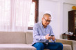 © gballgiggs - Senior asian man wearing glasses and using mobile phone at home,Relax time,Senior lifestyle concept,Long sighted