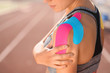 © Pixel-Shot - Sporty woman with physio tape applied on shoulder at stadium, closeup