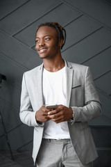 Portrait of stylish African-American man with mobile phone in room