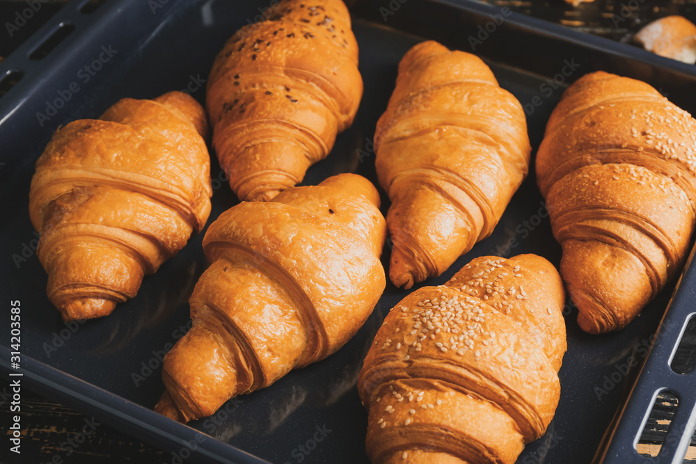 Tasty croissants on baking tray