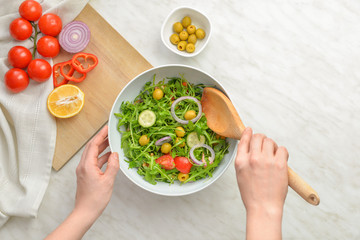 Woman making tasty salad at table