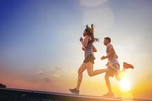 Young Couples Running Sprinting On Road. Fit Runner Fitness Runner During Outdoor Workout With Sunset Background
