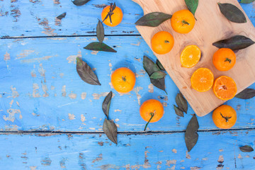 Wall Mural - Fresh mandarin oranges fruit or tangerines with leaves on wooden table, copy space