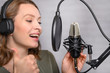 © Anton - Female vocal recording. Young girl with microphone and headphones in recording studio. Recording of vocal, blogger, reading text, voice acting.