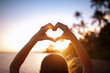 © kieferpix - Female making a heart shape on the beach at sunset. People love, nature symbol concept.