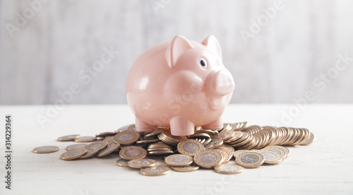 Fotografía Piggy bank with coins on the desk. Saving money