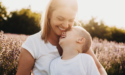 portrait of a beautiful young mother laughing while holding on her legs her little kid which is laug