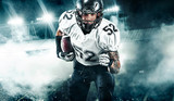 Fototapeta Sport - American football player. Sportsman with ball in helmet on stadium in action. Sport wallpaper. Team sports.
