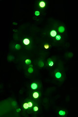 Blurred green lights on a black background. Vertical. UFO, digital, festive concepts.