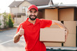 © Drobot Dean - Image of delivery man standing with parcel box and showing thumb up