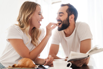 Wall Mural - Happy beautiful young couple having breakfast at the kitchen table