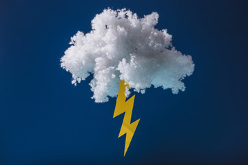 White fluffy cloud made of cotton wool with lightning isolated on dark blue