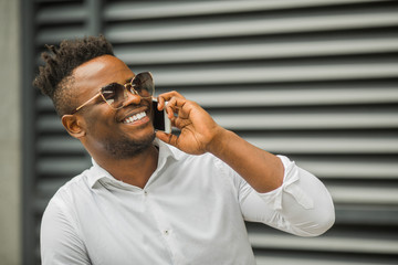 Wall Mural - handsome young african man in a white shirt with a phone in his hand