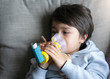 © Anchalee - Poor boy tired from chest coughing holding inhaler mask, Child closing his eyes while using the volumtic for breathing treatment,Tried Kid having asthma allergy using the asthma inhaler