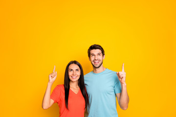 Photo of cute two people couple guy and lady hugging directing fingers up empty space low prices shopping wear casual blue orange t-shirts jeans isolated yellow color background