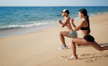 Healthy Lifestyle. Young Beautiful Couple Doing Sports Exercises At The Beach.