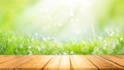 Wall Mural - Beautiful spring natural  background with green fresh juicy young grass and empty wooden table in nature morning outdoor.  Beauty bokeh and sunlight.