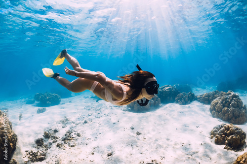 Fototapeta na szkło Freediver z płetwami ślizga się po piaszczystym dnie w błękitnym oceanie