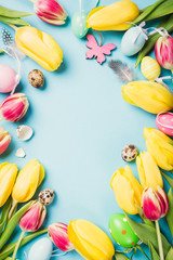 Wall Mural - Happy Easter card. Frame with yellow tulips and easter quail eggs with copy space for text on blue background. Top view.