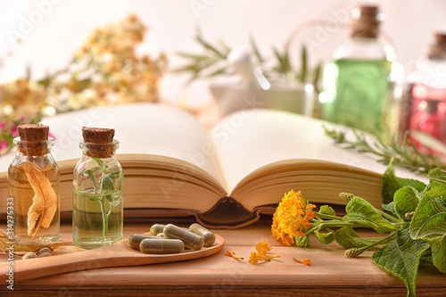 Fotomural Traditional medicine with herbs and book on table front view