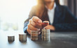 © Farknot Architect - Businesswoman holding and stacking coins on the table