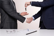 two men in suits shake hands and give keys after buying a house