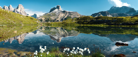 Awesome Alpine highlands in sunny day. Amazing Summer Landscape of Dolomites Alps. Wonderful Panoramic view at Mountains Range and calm lake on foreground of Tre Cime di Lavaredo National park