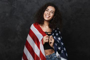 Sticker - Image of young nice woman smiling at camera and holding american flag