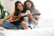 © Drobot Dean - Loving couple indoors at home play on guitar.