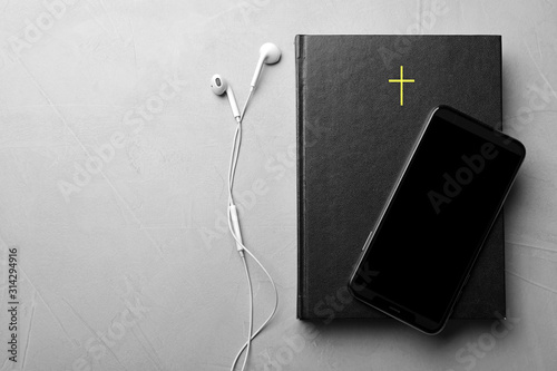 Fotomural Bible, phone and earphones on light grey background, flat lay with space for text