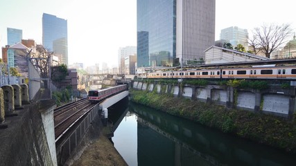 Canvas Print - Train passing on the bridge in the Tokyo city across the bridge and city view in the background.Tokyo's train/subway train moving in city center of Tokyo.Tokyo Olympic 2020 4K UHD video transportation