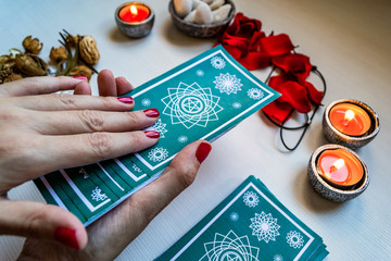 fortune teller with green tarot cards on a white wooden table ba