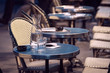 Paris cafe tables with wter carafe and glass and wicker chairs