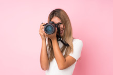 Young Blonde Woman Over Isolated Pink Background With A Professional Camera